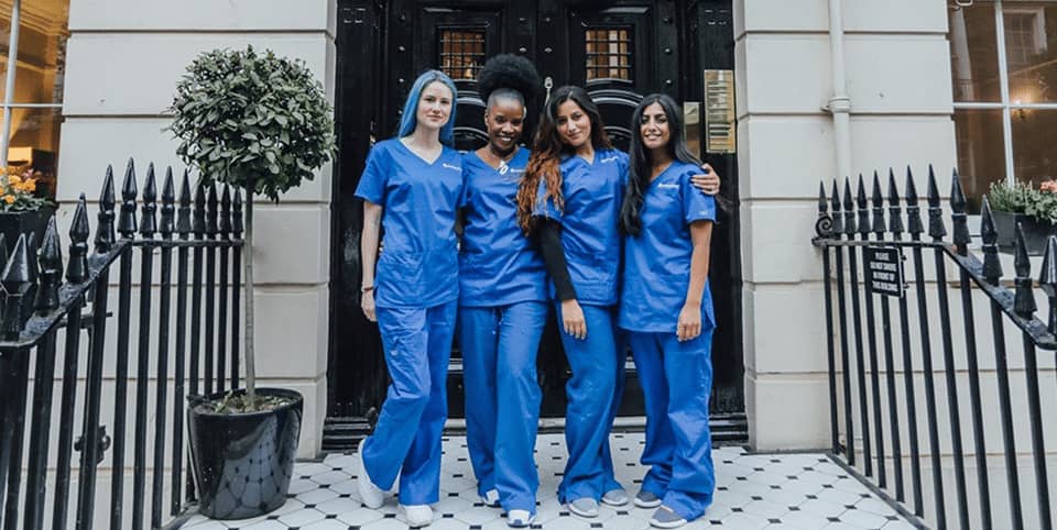 Four nurses in blue scrubs outside a Georgian clinic entrance for CoolSculpting fat freezing in Dublin